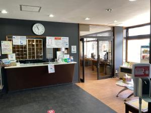 函馆Hotel Tetora Yunokawaonsen - Vacation STAY 30541v的墙上挂着时钟的办公室和柜台