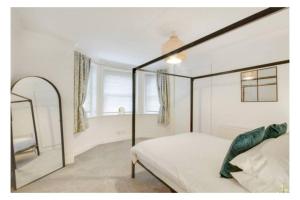 皇家滕布里奇韦尔斯Central 2 bedroom garden flat with free parking的一间卧室配有天蓬床和镜子