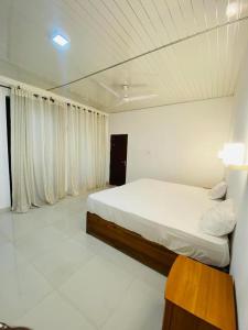 波隆纳鲁沃New hotel canel park的白色卧室配有床和木桌