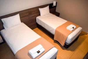 利马Hotel Mega的配有白色床单的酒店客房内的两张床