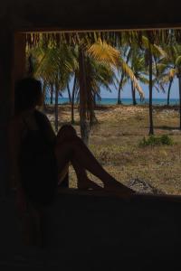 马塔迪圣若昂Blue praia de Santo Antônio的坐在窗户旁的一位女士,她看着海滩