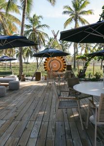 马塔迪圣若昂Blue praia de Santo Antônio的一个带桌椅和遮阳伞的甲板