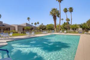 棕榈泉Palm Springs Condo 3 Fenced Patios, Pool Access的一个带椅子和棕榈树的大型游泳池