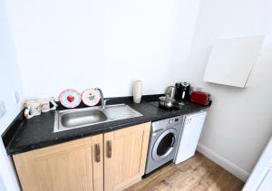 伦敦Cute Studio Garden Flat, 5 min to tube的厨房配有水槽和洗衣机