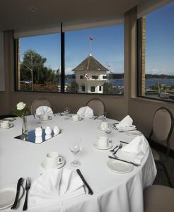 纳奈莫海滨堡垒酒店的一间设有白色桌子并享有水景的用餐室