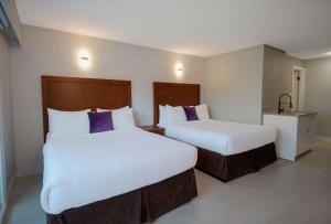 伯纳比Coast Metro Vancouver Hotel的配有白色和紫色枕头的酒店客房内的两张床