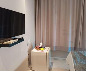 坎普斯戈伊塔卡济斯APART HOTEL AMÉRICA的客厅配有电视和白色桌子