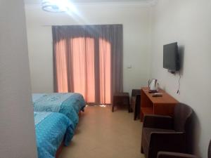 艾因苏赫纳Lasirena Resort Aqua Park-Family Only的一间卧室配有一张床、一张书桌和一台电视
