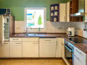 马林费尔德Ferienhaus Seemannsruh Wohnung mit Wasserblick und abgeschlossenem Grundstück的厨房配有白色橱柜、水槽和窗户。