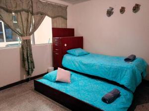 克萨尔特南戈Casa completa en Xela的一间卧室设有两张带蓝色床单的床和窗户。
