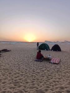 BawatiAbo Yusre Sfari的坐在海滩上的人,有两顶帐篷