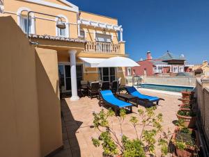 托雷德尔马尔Viña Home的房屋设有带椅子和遮阳伞的庭院