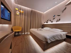 新加坡Wink Hotel @ Bugis的一间卧室配有一张大床和一张黄色椅子