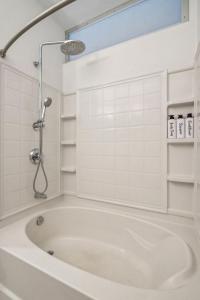 明尼阿波利斯CozySuites Mill District pool gym # 05的浴室铺有白色瓷砖,配有浴缸。