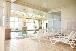 康康Hippocampus resort的一间设有白色椅子的房间和一个游泳池