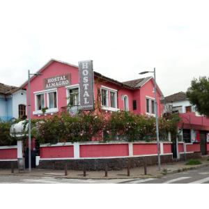 基多Hostal Almagro的粉红色的建筑,前面有标志