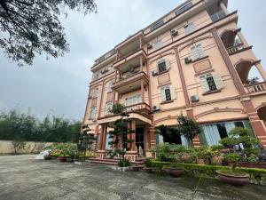Yên BáiKhách sạn Phương Thuý 1的前面有盆栽植物的大粉色建筑