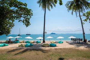瑶亚岛Royal Yao Yai Island Beach Resort的沙滩上,有遮阳伞,有人坐在沙滩上
