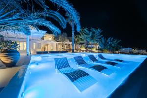 米克诺斯城Sanarte Villas Mykonos的夜晚的游泳池,灯光蓝色