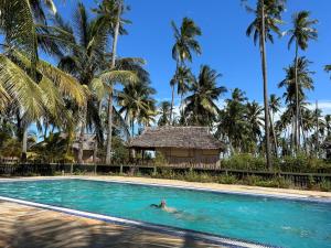 MkwajaBarry's Beach Resort的在棕榈树泳池游泳的人