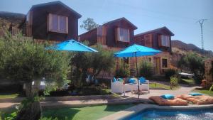 奇利亚龙-德昆卡Cabañas El Descansito的游泳池畔的两把蓝色遮阳伞和椅子