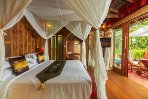 小通奈潘Santhiya Koh Phangan Resort and Spa的卧室配有带窗帘的大型白色床