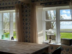 朗格内斯岛Huus Hannchen的客房设有2扇窗户和1张带台灯的桌子。