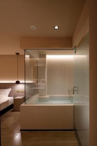 东京HotelCO Kuramae ホテル コ 蔵前的一间设有床铺的客房内的玻璃淋浴间