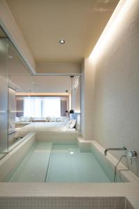 东京HotelCO Kuramae ホテル コ 蔵前的带浴缸的浴室,后面配有一张床