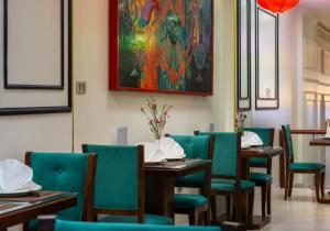 河内Bella Rosa Hotel & Travel的一间带桌椅的用餐室和一幅画
