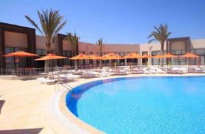比塞大App S1 à l'hôtel Andalucia Beach的一座带橙色遮阳伞和椅子的大型游泳池