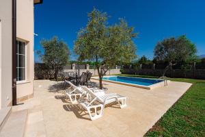 蒂瓦特Villa Stemi的一个带白色椅子的庭院和一个游泳池