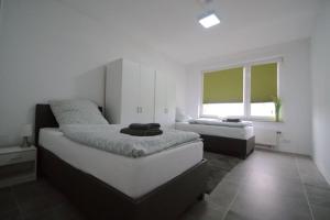 贝尔吉施格拉德巴赫Frühlings Apartments GL21的一间白色卧室,配有两张床和窗户
