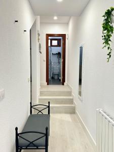 柯米拉斯Apartamentos Val de Comillas的走廊上设有白色的墙壁和楼梯,门上设有门