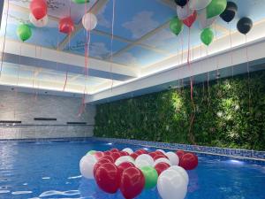 科威特Costa Del Sol Hotel by Arabian Link的天花板上悬挂着红色和白色气球的游泳池