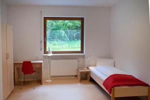 柏林Umwelt Bildungszentrum Berlin的一间卧室配有一张床、一个窗口和一张书桌