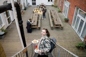 伦敦Wombat's City Hostel London的站在一个有一盘食物的阳台上的女人