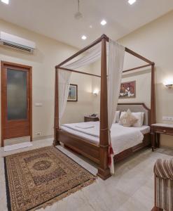 孟买Elphinstone Hotel的一间卧室配有一张天蓬床和地毯。