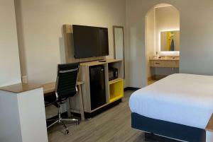 亨博尔杭博/休斯敦洲际机场戴斯酒店的一间卧室配有一张床和一张书桌及电视