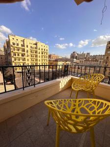 开罗Economy room in Downtown的阳台配有两张黄色椅子和一张桌子