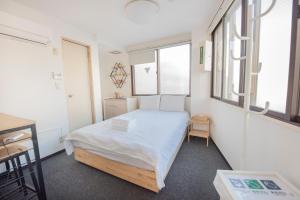 东京入谷windhouse的一间卧室配有一张带白色床单和窗户的床。