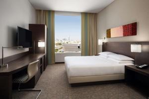 利雅德Hyatt Place Riyadh Sulaimania的配有一张床、一张书桌和一扇窗户的酒店客房