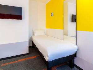 乌德蒙greet Hotel Nancy Sud的一张小床,位于拥有黄色和白色墙壁的房间