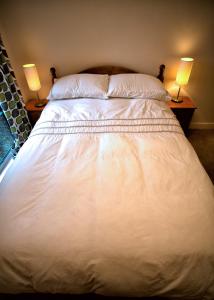 索尔兹伯里索尔兹伯里奢华公寓的一张白色大床,两台桌子上放着两盏灯