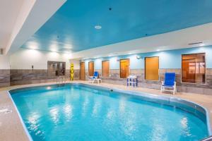 欧文斯伯勒Wingate by Wyndham Owensboro的大楼内带蓝色椅子的大型游泳池