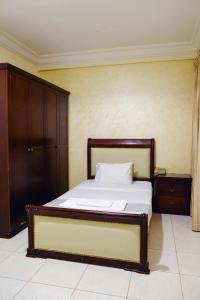 多哈Liberty Avenue Hotel的一间卧室配有一张带木制床头板的床