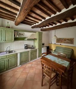 圣吉米纳诺农庄卡萨酒店的厨房配有绿色橱柜和木桌