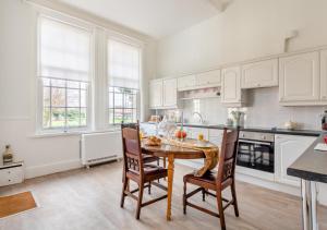 StradsettThe Lake House - Crimplesham Hall的厨房配有白色橱柜和桌椅