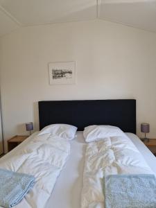 劳雷尔苏格Chalet的一张带白色床单和黑色床头板的床