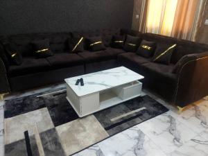 瓦加杜古Cool meuble 2的客厅配有黑色沙发和白色咖啡桌